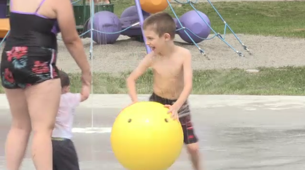 Little boy plays in the water of a splash pad