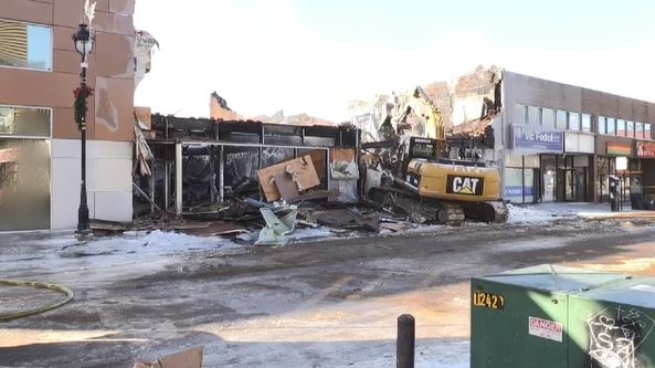 An excavator tears down burned out buildings